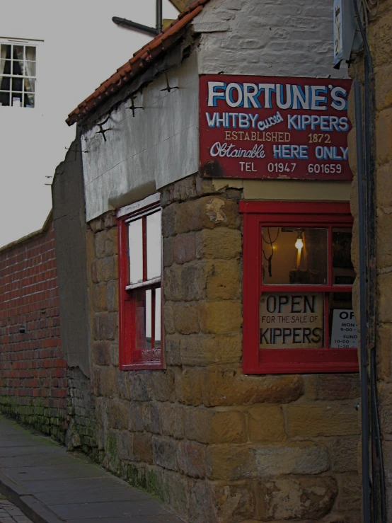 the corner of an old building has a broken sign