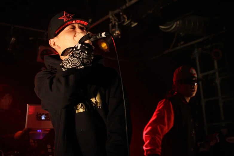 a man is standing on a stage while wearing a bandanna and listening to the microphone