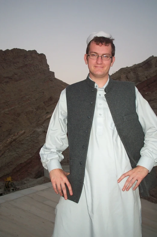 a man wearing white clothes with mountains in the background