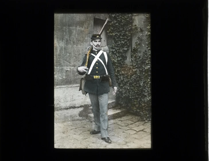 a man wearing a uniform standing with his rifle