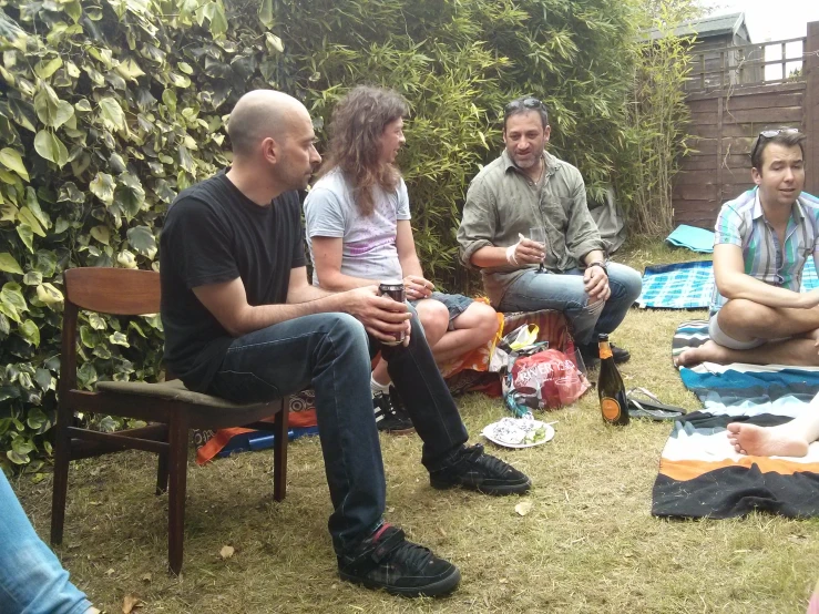 four people sitting on a lawn on picnics