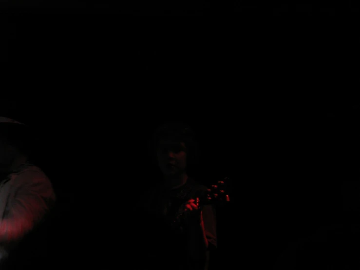 two men standing in the dark holding their hands