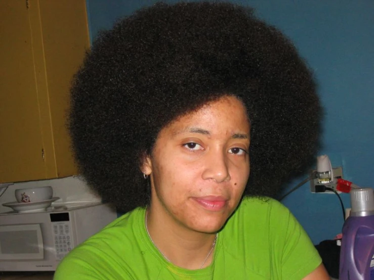 woman with afro in kitchen next to bottle of cleaner