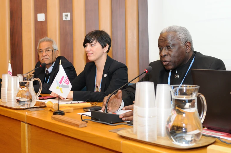 three people seated at a table with papers in front of them