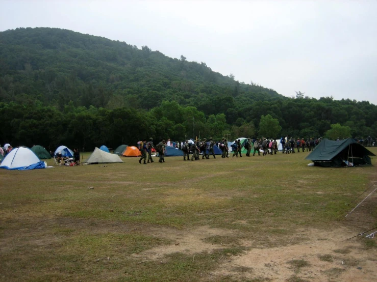 a crowd of people gathered around tents at an outdoor event