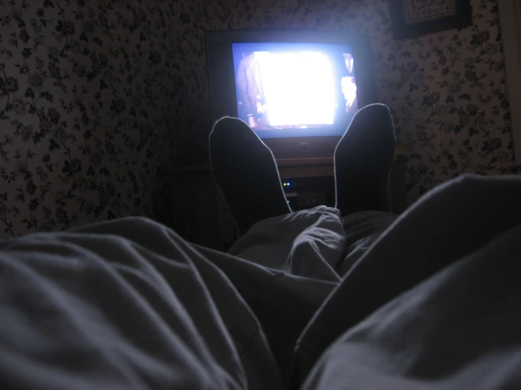 someone who is in bed watching a television