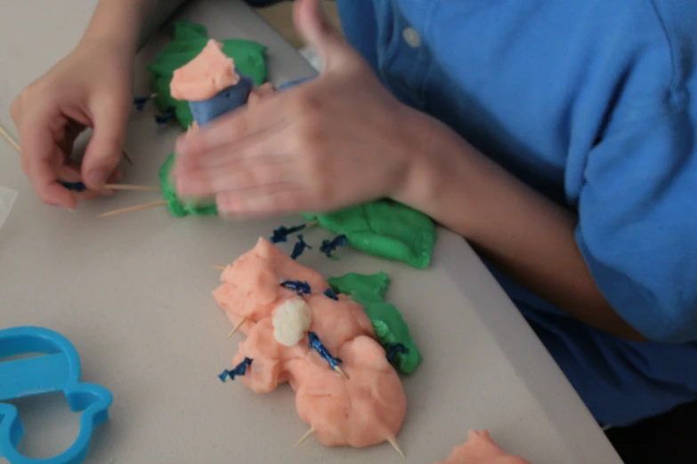 a child is making cookies with some green frosting