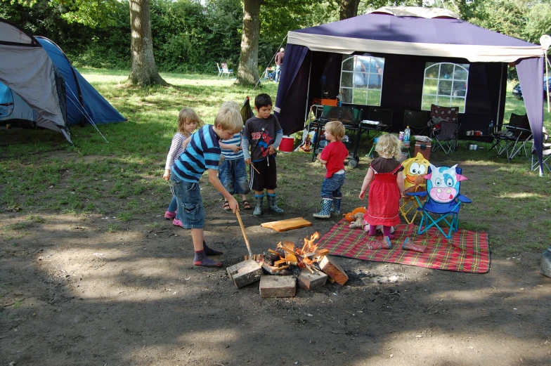 a group of young children standing around a fire pit