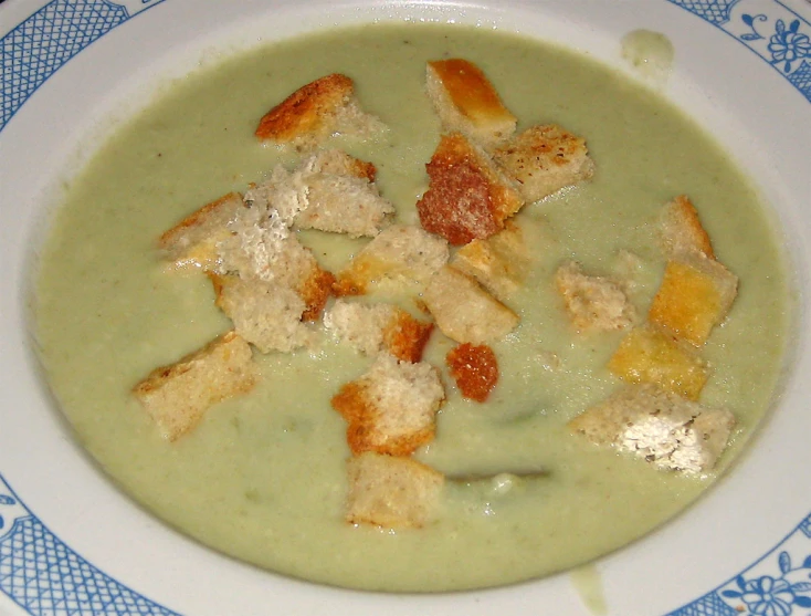 a white bowl filled with broth and croutons