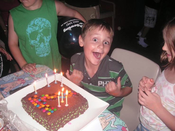 a boy with a birthday cake in his hands at the table