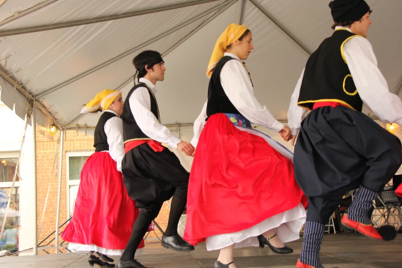 three men and a woman dancing under a tent