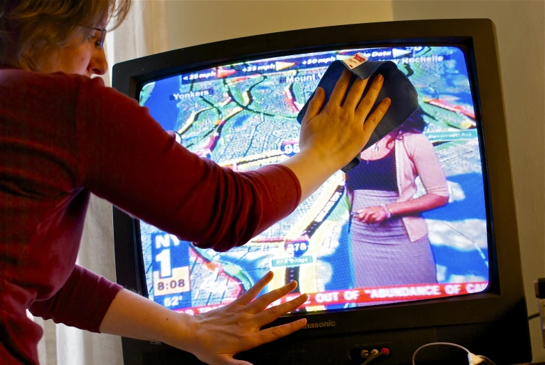 a woman wiping off her hand on the television
