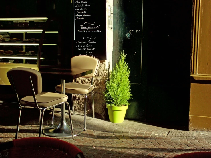 two chairs and one table are outside in front of a cafe