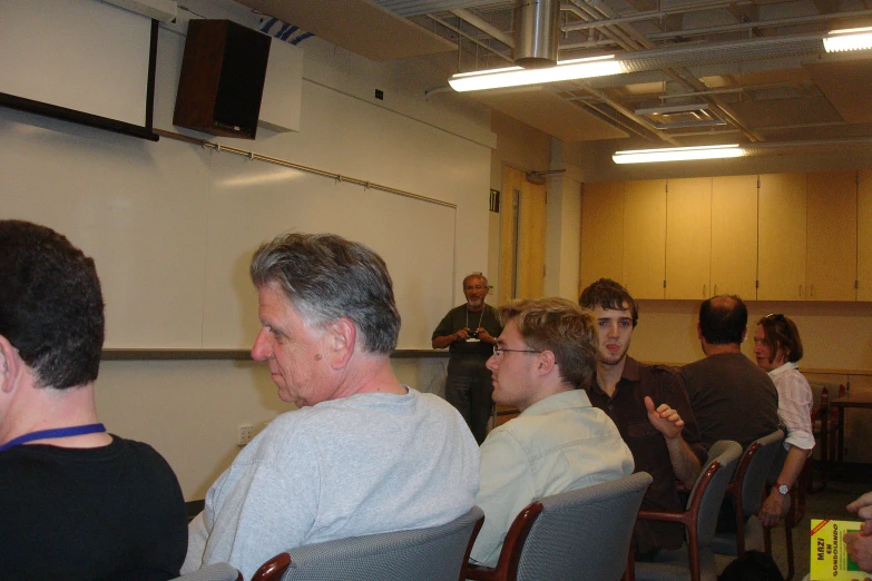 a group of people are seated in front of a panel