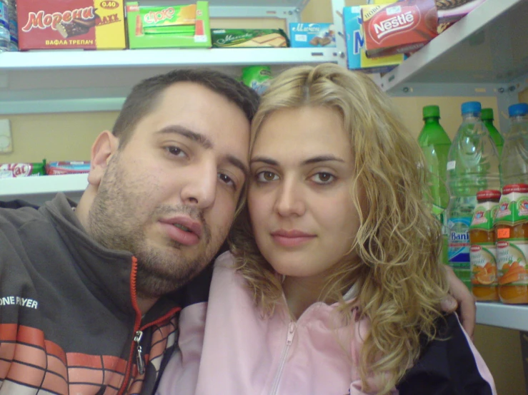 a close up of two people near a shelf with beverages