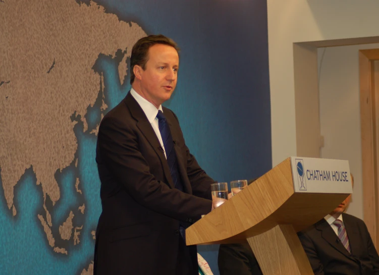 a man standing in front of a podium wearing a suit and tie