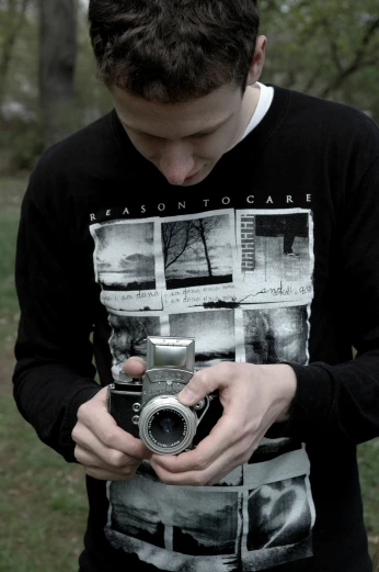 a boy holding his camera in one hand and his other hands over the camera