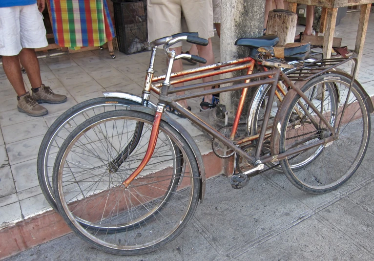 a bicycle sitting up against a post outside