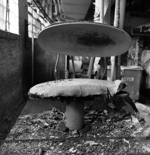 an old mushroom - shaped table sits abandoned near brick wall