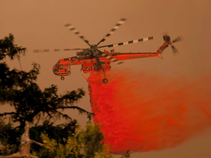 a large helicopter is flying very high over the trees