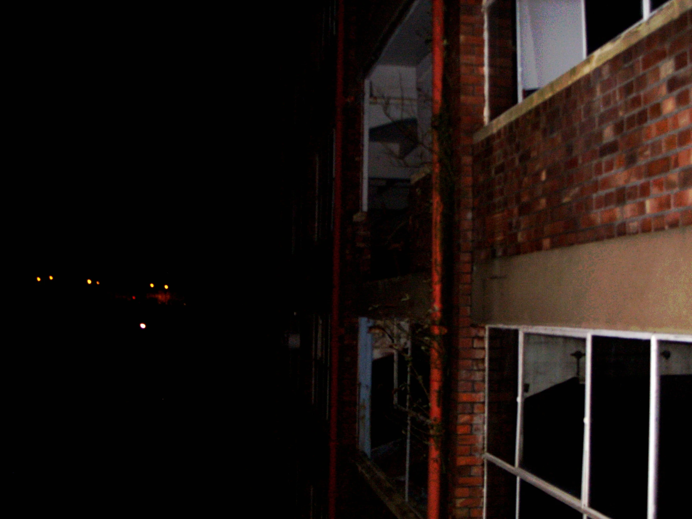 a window with bars is at night next to the street