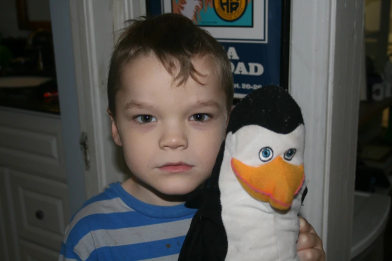 the small child holds up his stuffed penguin