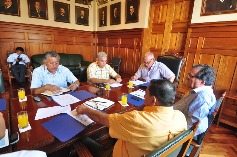 a group of older men sitting around a wooden table