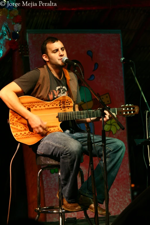 a man sitting in a chair while playing a guitar