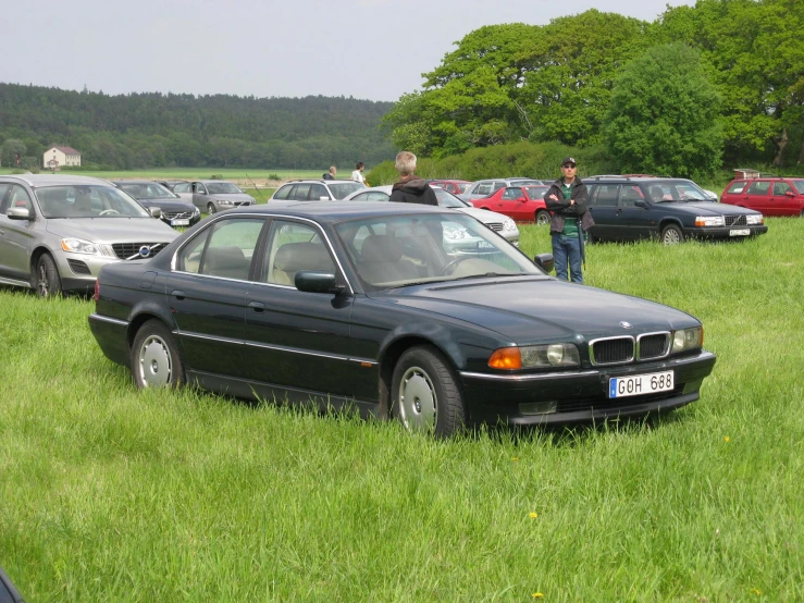 a couple of men stand by a parked car