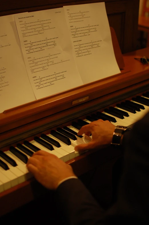 two person playing the piano and some sheet music behind them