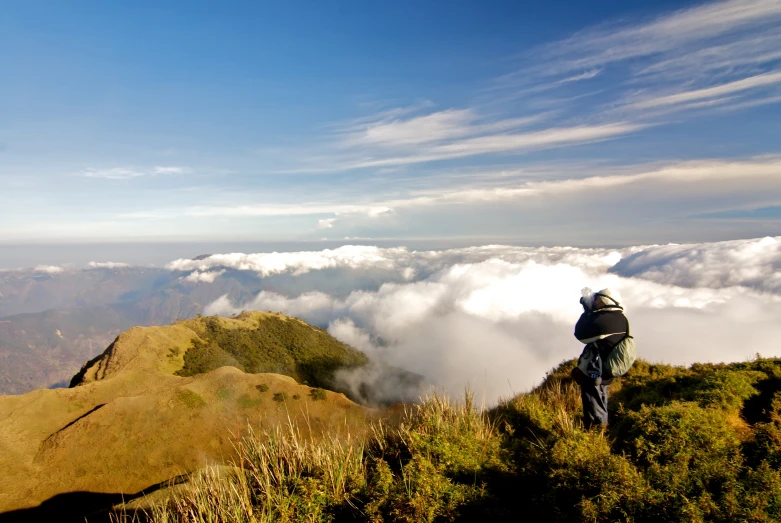 the man stands at the edge of a grassy hillside