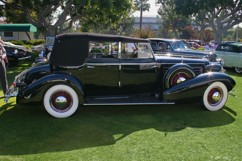 an antique car with white trim on display in a park