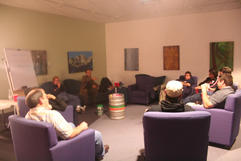 people sitting in chairs talking and interacting in a room