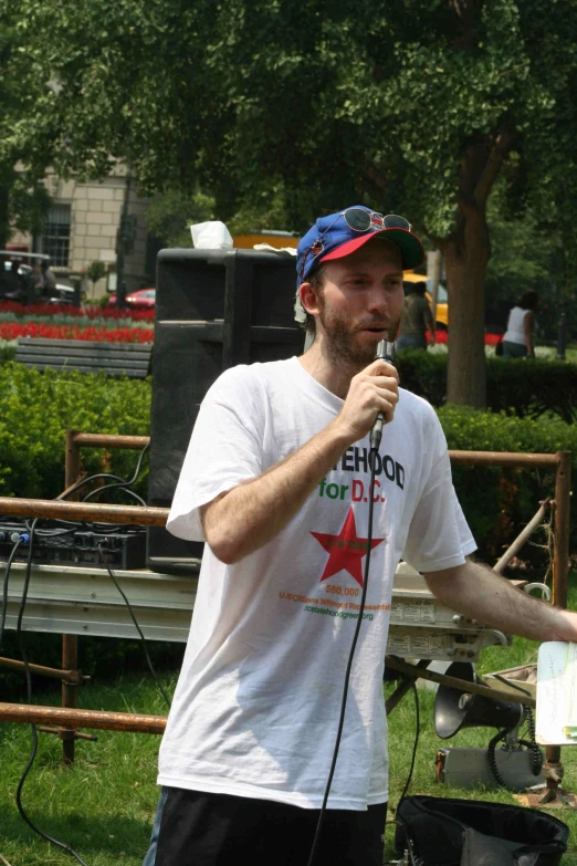 a man is standing in the grass with a microphone