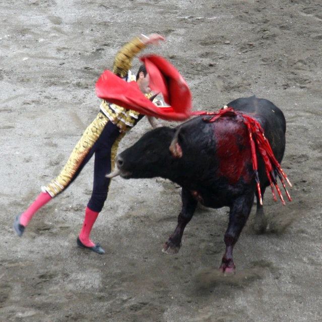 a man is fighting a black bull in an open area