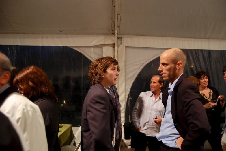 many people standing in front of a white tent