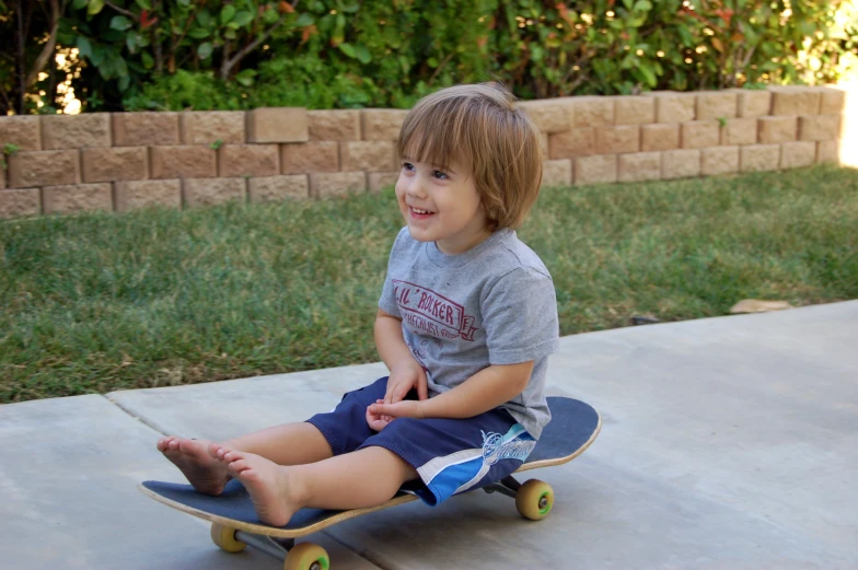 a young child sitting on a skateboard in a yard