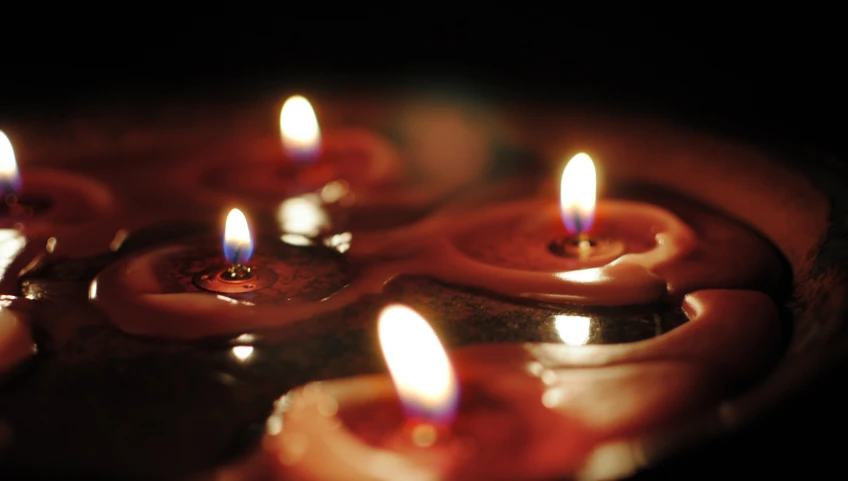 lit candles glowing bright, are in a dish