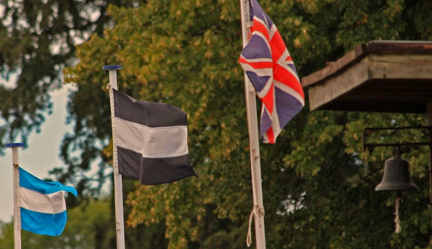 three different flags sitting in front of a large building