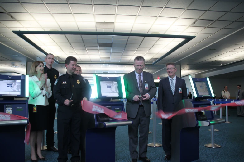 men standing at an airport gate with a red ribbon