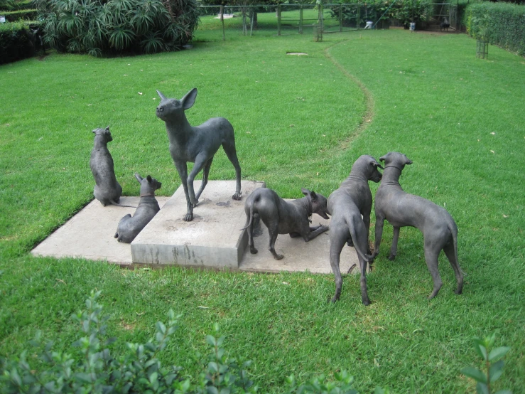 sculpture of dog and kitten on concrete platform in garden