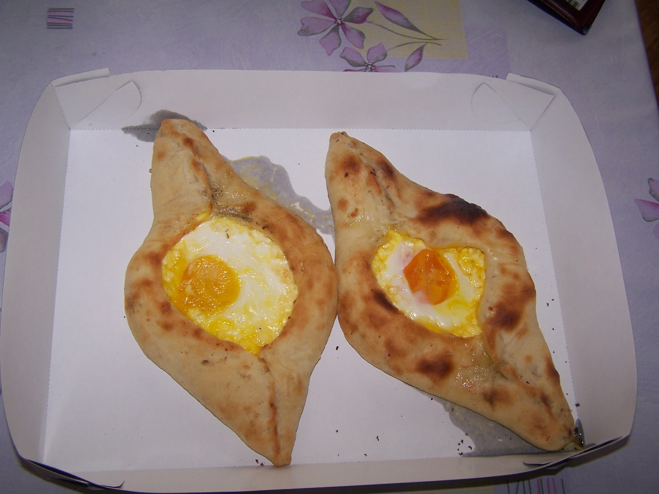 two slices of pizza with an egg in a heart shaped dish