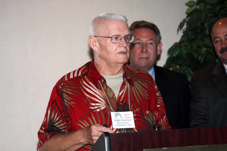 two men standing behind a podium while wearing glasses