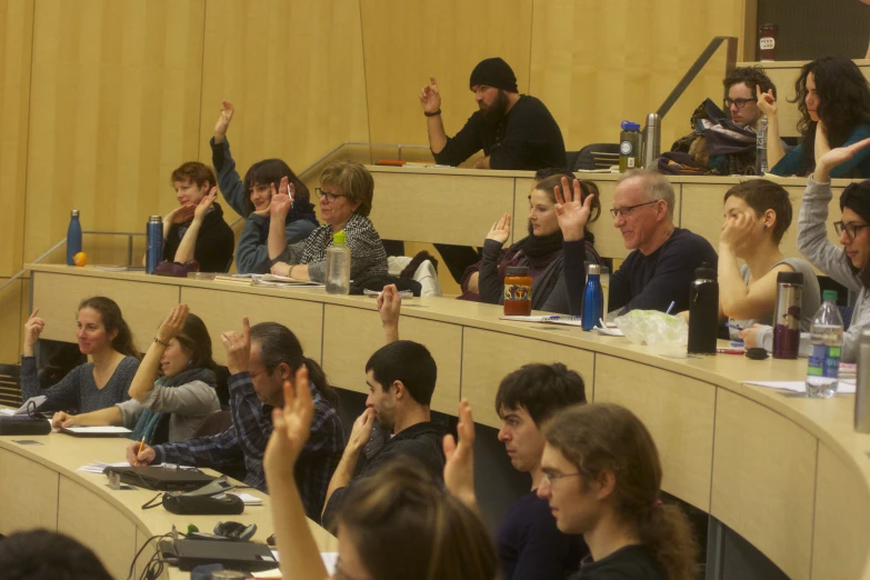 people sitting at tables with their hands raised in the air