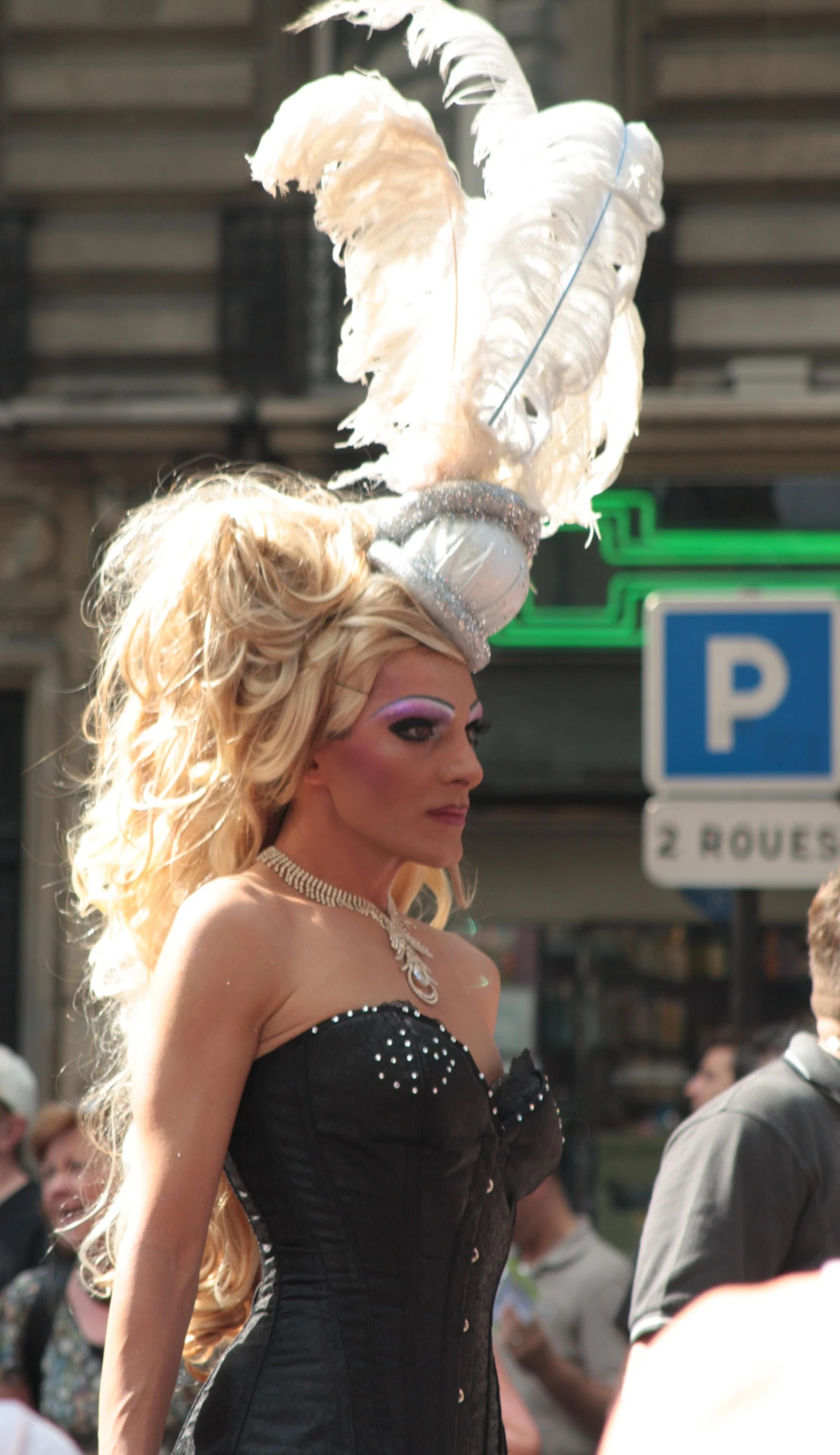 a woman wearing a hat with feathers in front of a street