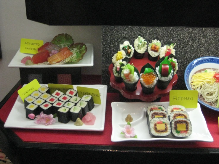 a table set up with sushi, pasta, and vegetables