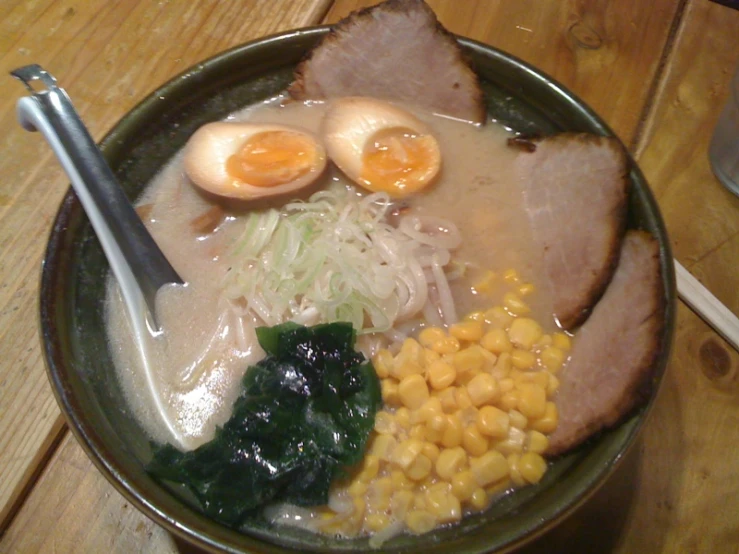 a bowl of food with two boiled eggs, corn and other vegetables