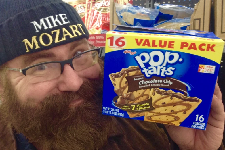 a man wearing a knit hat and glasses is holding up his pop tarts box