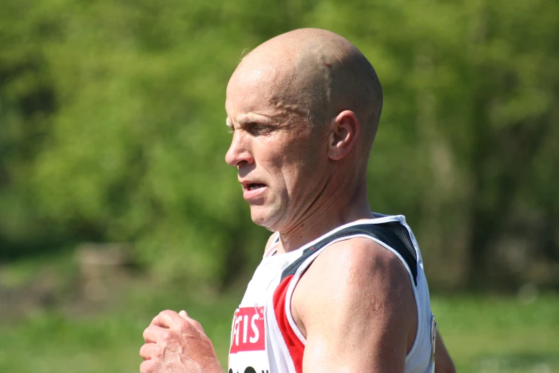 man wearing a vest running a race with trees in the background