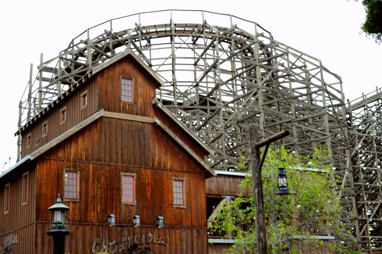 an old red and gray roller coaster in a large park